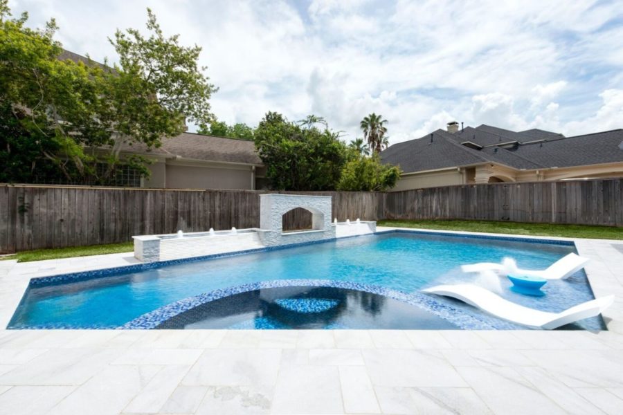 Backyard tiled pool with spa and tanning shelf in Humble Texas